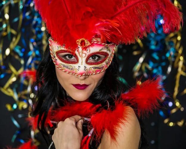 Mulher fantasiada com plumas e máscara veneziana ilustra o que vender no Carnaval